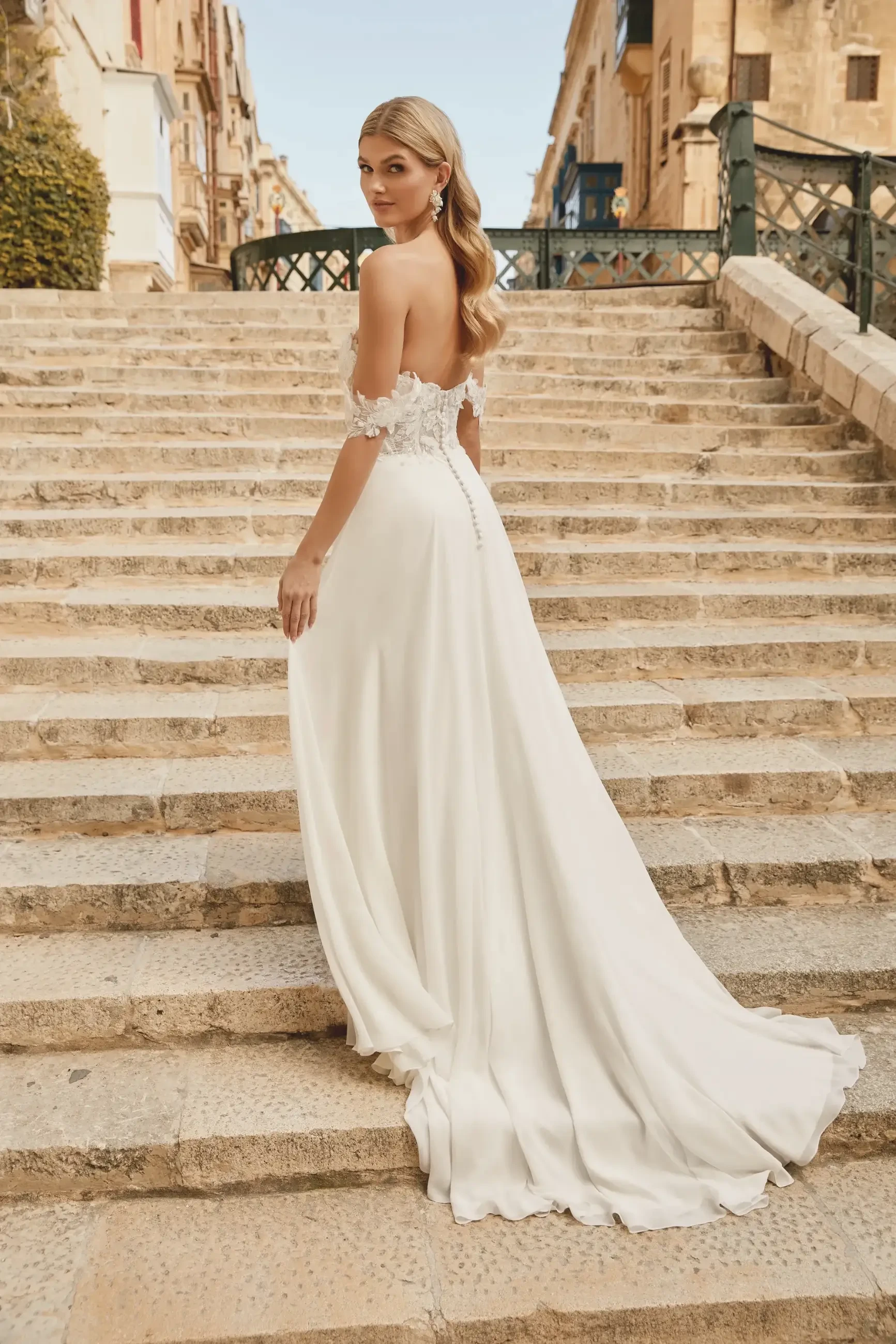 model is wearing an off the shoulder chiffon A-line wedding dress with embroidered lace and 3D floral appliques