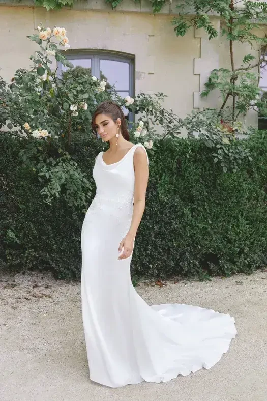 Model is wearing a charmeuse fit and flare wedding dress with a cowl open back