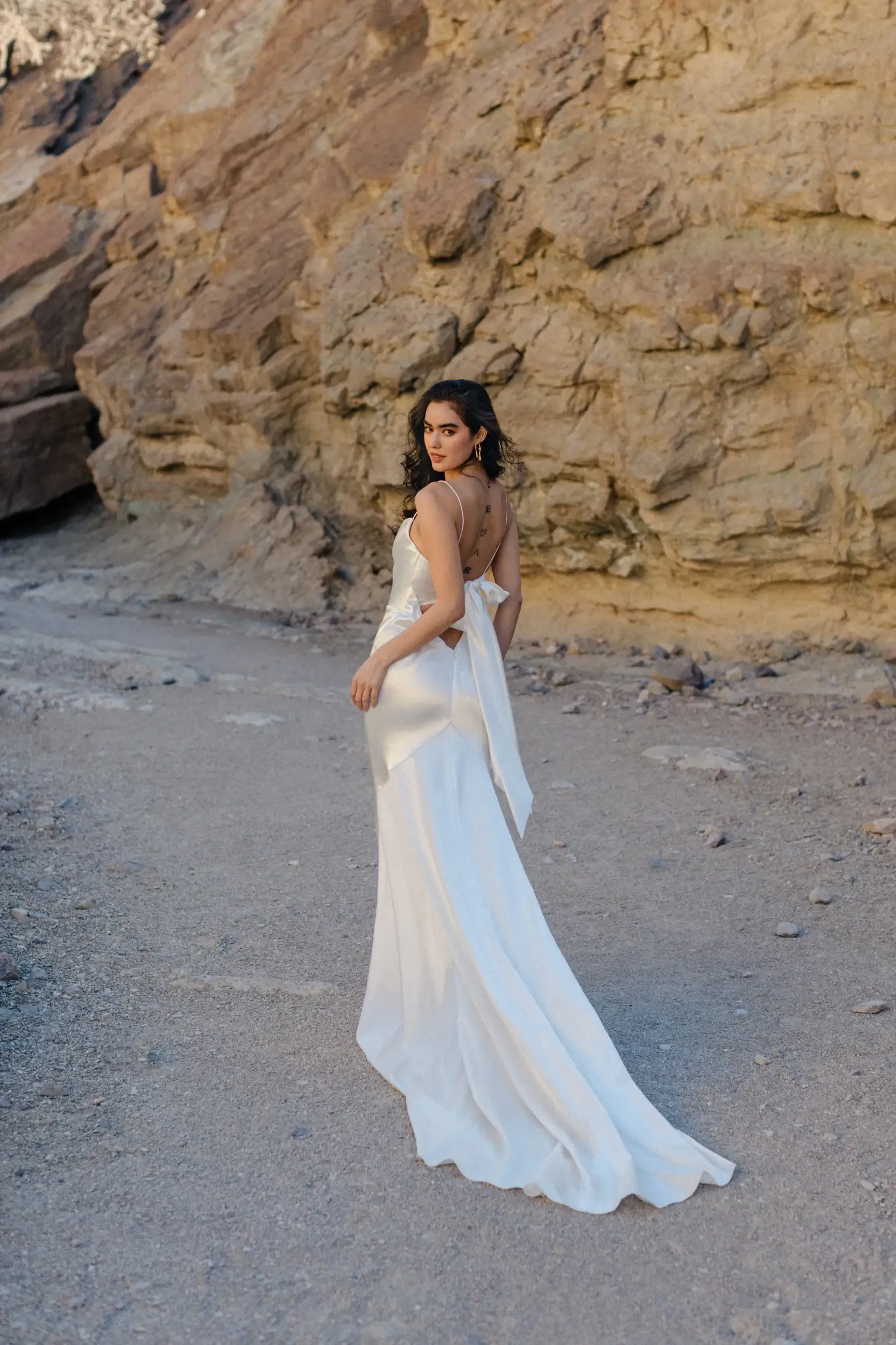 model is wearing a sleek satin sheath wedding dress