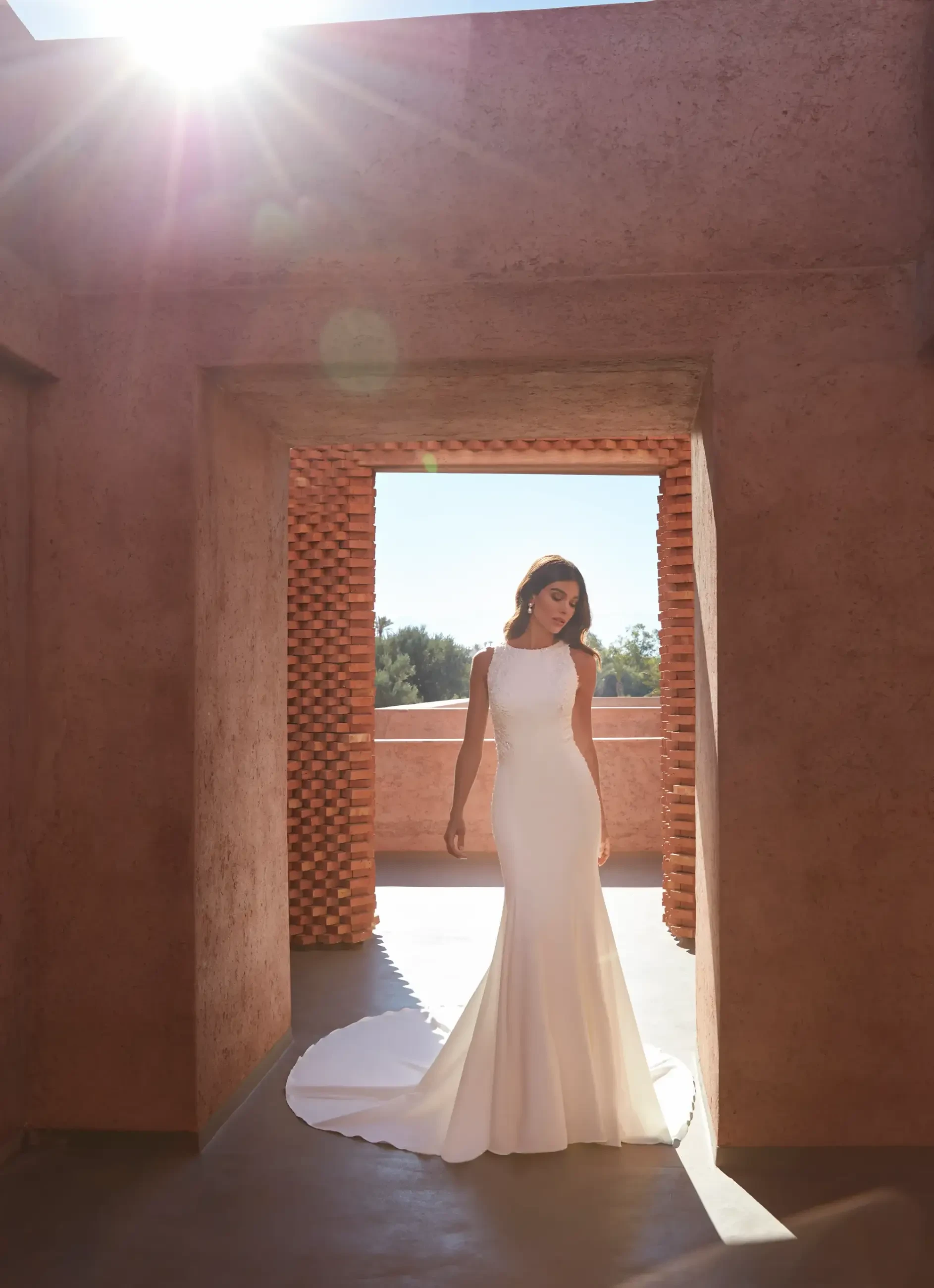 Model is wearing a sleeveless high neck wedding dress with a keyhole back