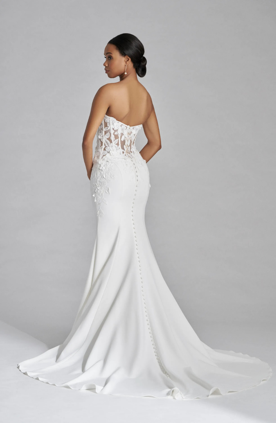model is wearing a strapless lace fit and flare bridal gown