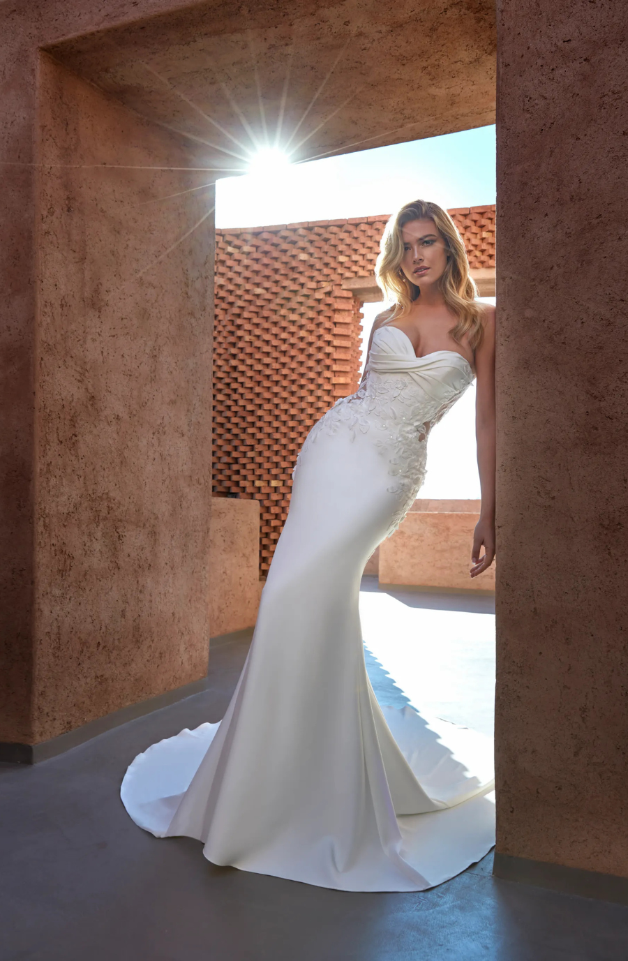 model is wearing a strapless lace fit and flare bridal gown