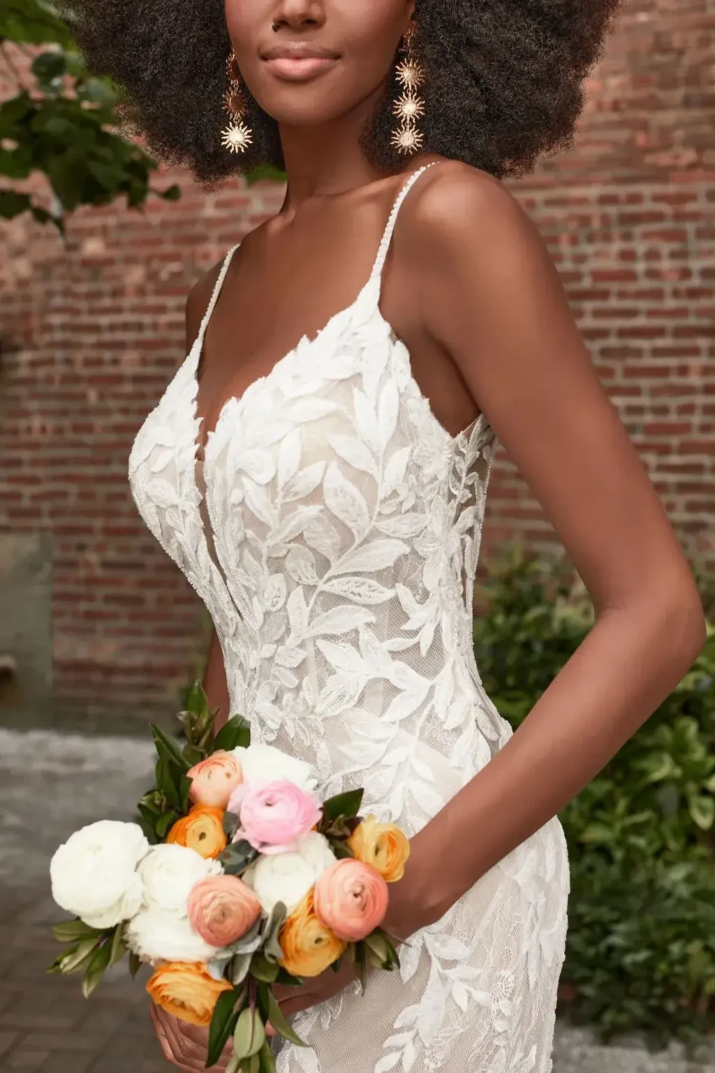 Model is wearing a lace sleeveless wedding dress with a train