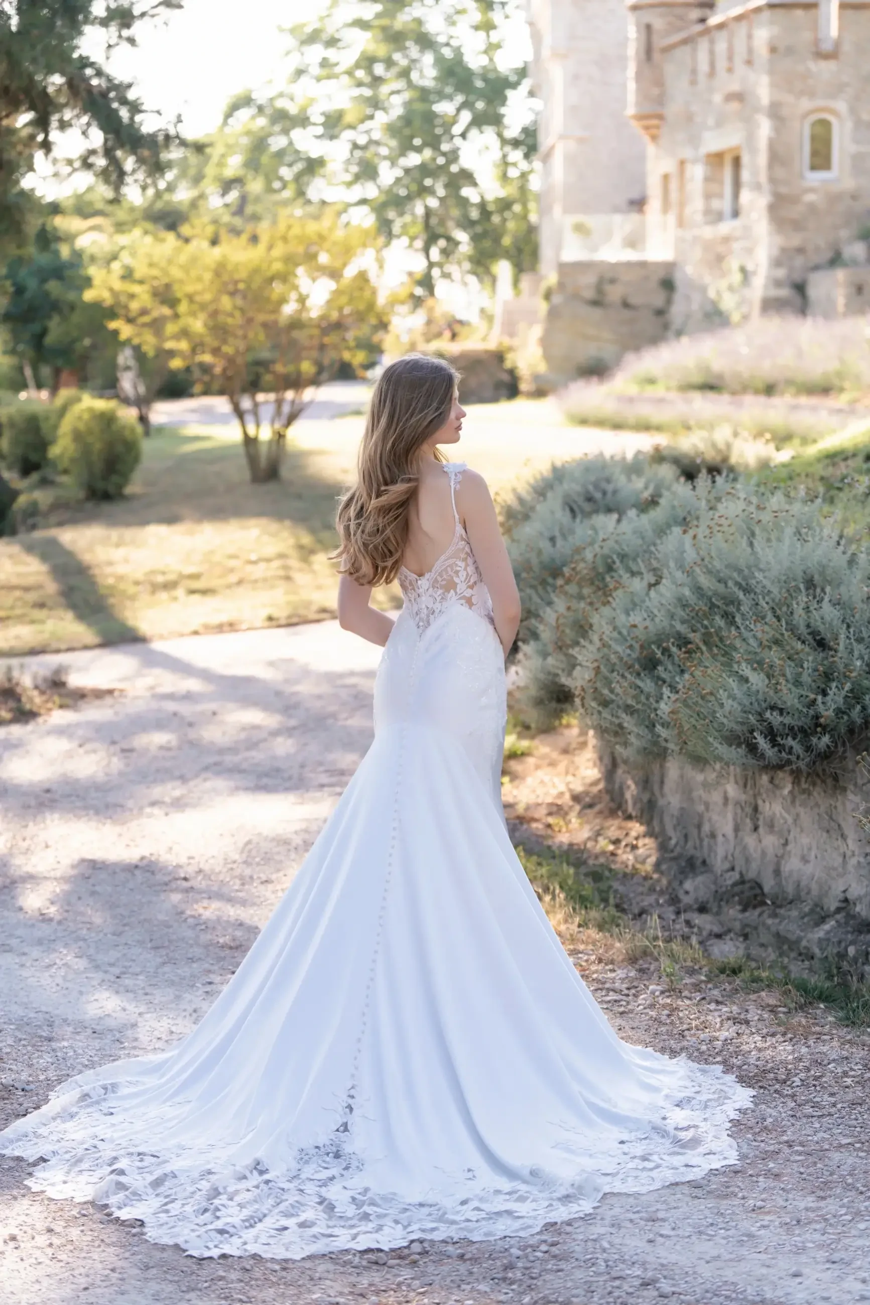 Model is wearing a satin sheath bridal gown with sequin lace appliques and a sleeveless bodice