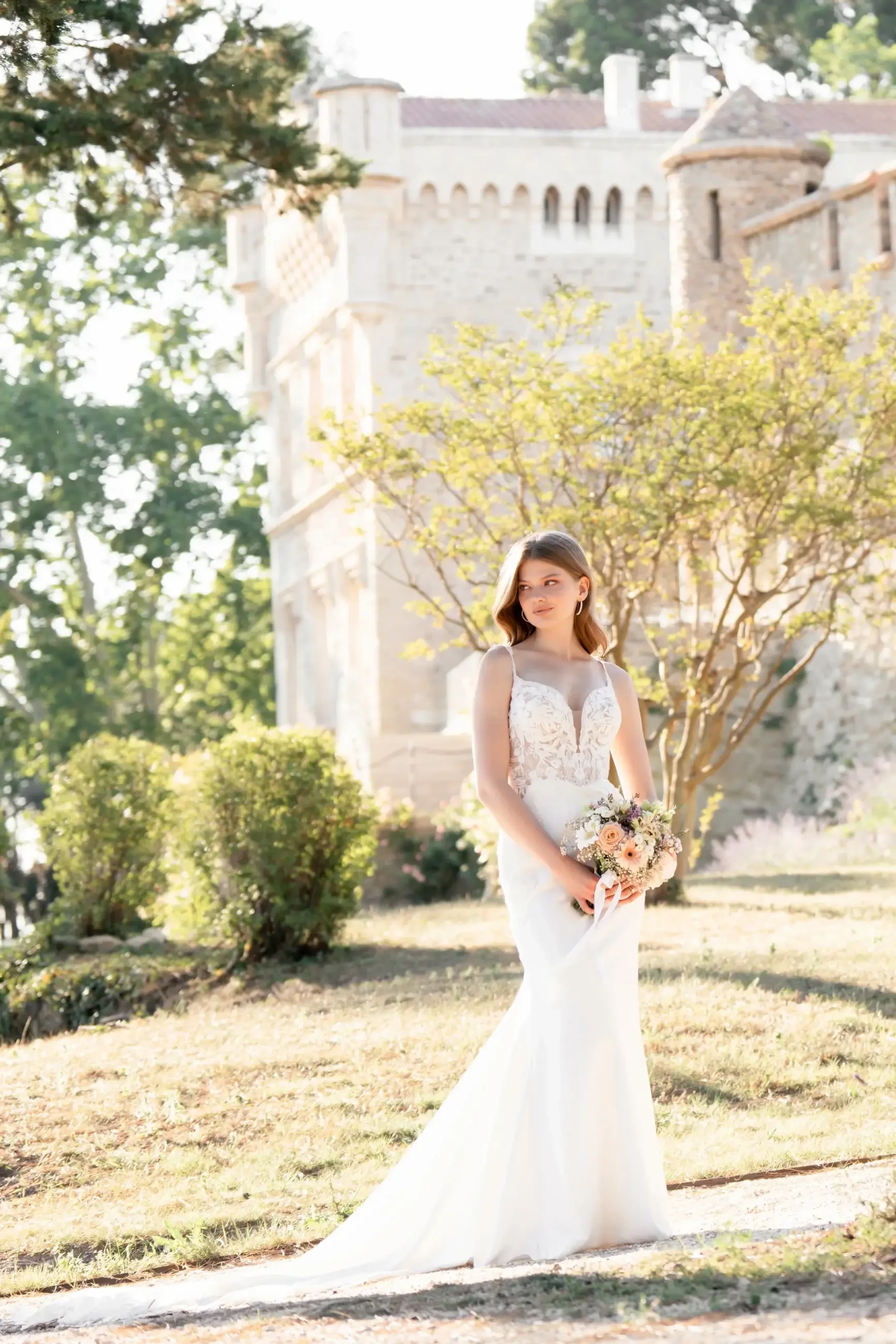 Model is wearing a satin sheath bridal gown with sequin lace appliques and a sleeveless bodice