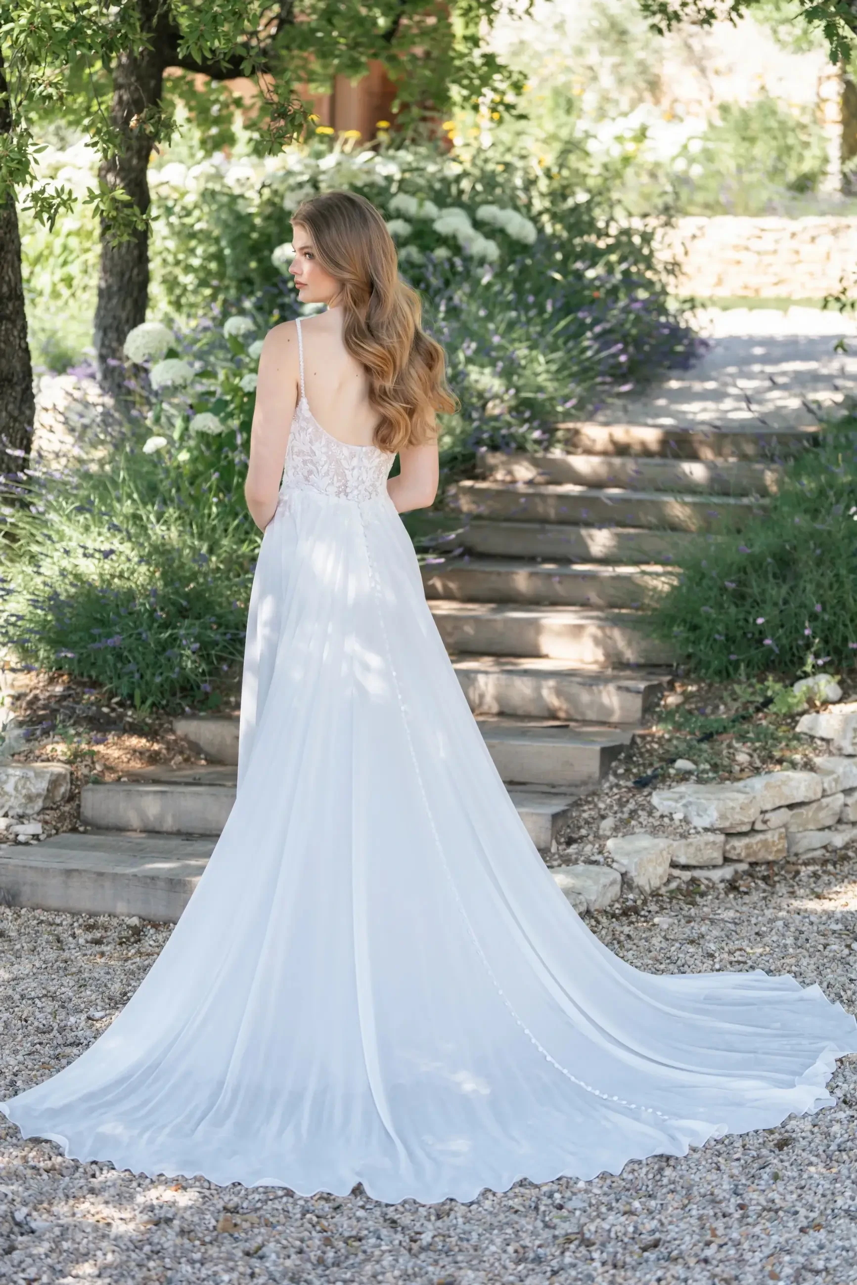Model is wearing an a-line chiffon wedding dress with beaded sequin lace appliques